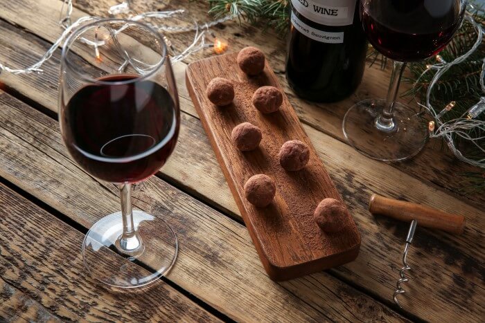 Tábua com chocolates acompanhada com uma taça de vinho