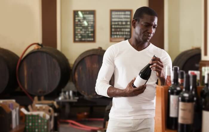 Homem escolhendo vinho em adega
