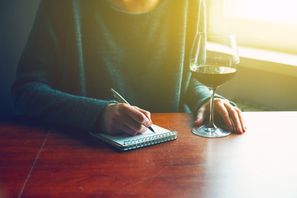 Pessoa Tomando Vinho E Fazendo Anotações