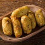 Seis bolinhos de bacalhau dentro de uma cumbuca.