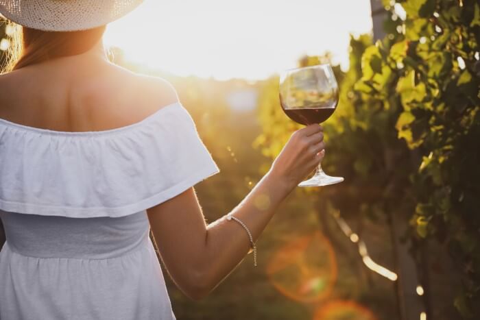 Mulher tomando vinho solidário em meio aos vinhedos