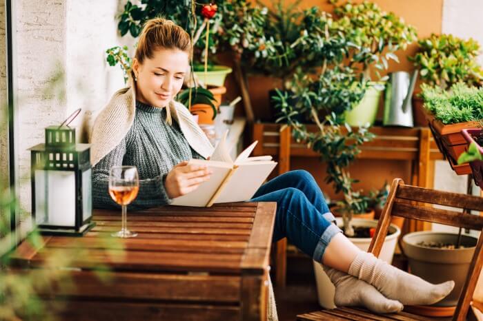 mulher degustando vinho em casa enquanto lê
