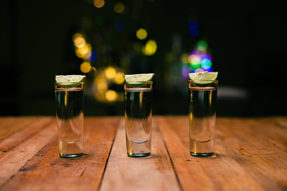 Imagem de três shots com tequila. Na borda de cada um deles há uma fatia de limão.