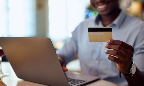 Homem Negro Escolhendo Vinho No Computador, Segurando Um Cartão De Crédito, Na Black Friday.