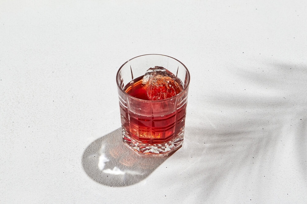 Foto De Um Copo Com Um Drink Com Campari Sob Um Fundo Branco.