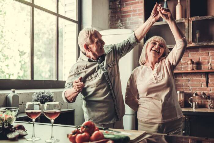 casal de idosos dançando na cozinha comemorando com vinho o dia dos namorados