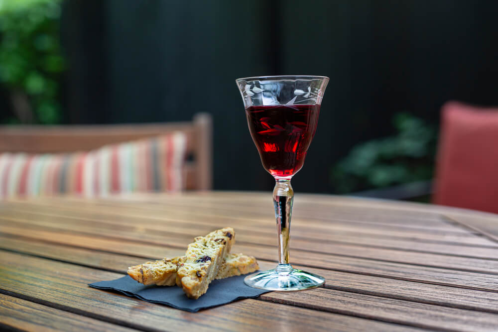 Imagem de uma taça com um vinho de sobremesa dentro. ao lado, é possível notar fatias de pão.
