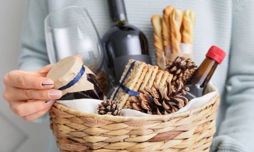 Uma Pessoa Segura Uma Cesta Com Vinho E Produtos Gourmet, Além De Uma Taça.