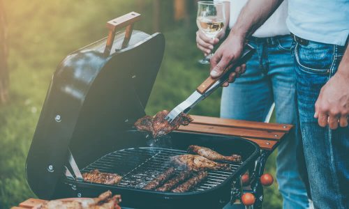 Imagem De Um Homem Fazendo Um Churrasco. Na Imagem, Ele Está Segurando Uma Taça De Vinho.