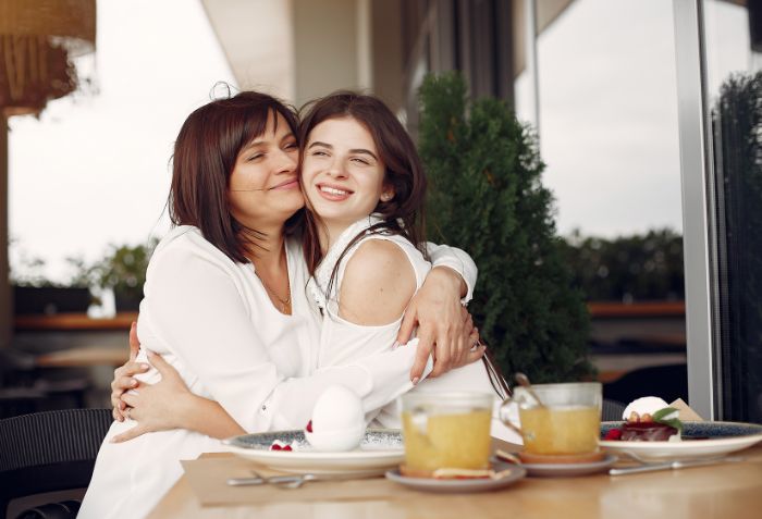 Mãe e filha abraçadas e almoçando