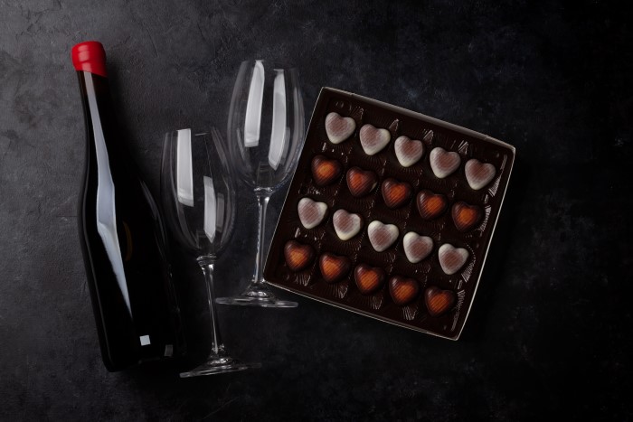 Vinho, taças e uma caixa de bombom de chocolate.