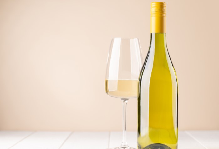 Garrafa e taça com vinho branco.