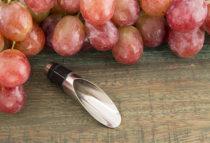 Bico dosador de vinho com uvas.