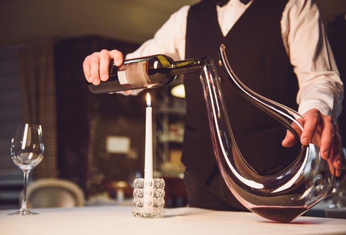 Garçom servindo vinho em decanter em restaurante.