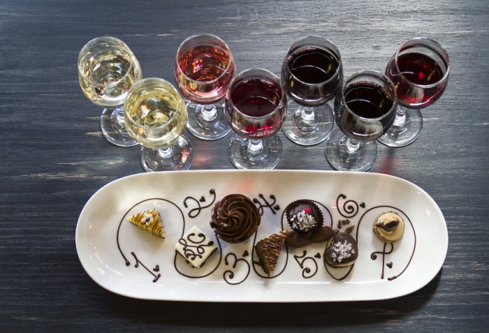 Minitaças de vinho com diversos tipos de vinho e doces para acompanhar.