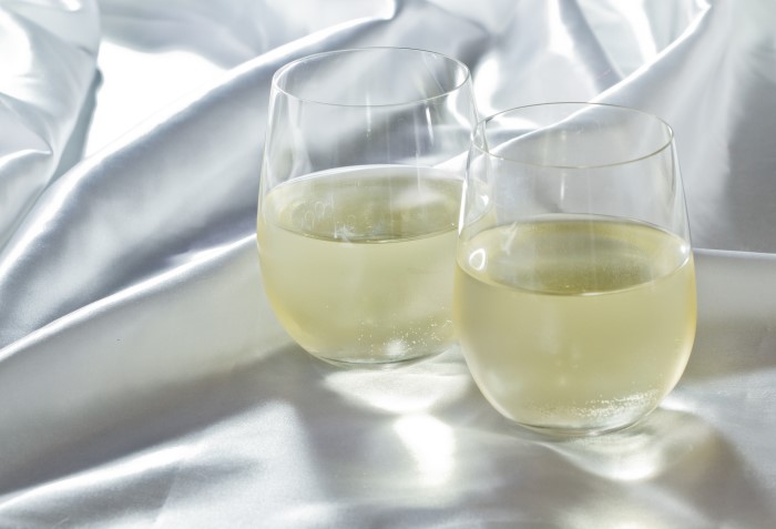 Duas taças de vinho sem haste com vinho branco.