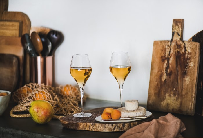 Vinho laranja sobre mesa com queijo e tábuas.