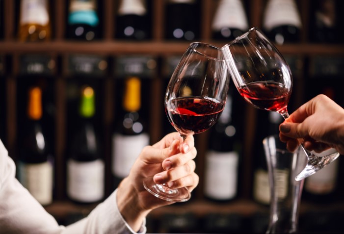 Pessoas bridando com taça de vinho tinto.