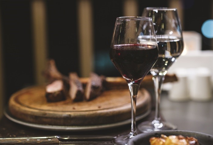Taças de vinho branco e tinto com carne vermelha.