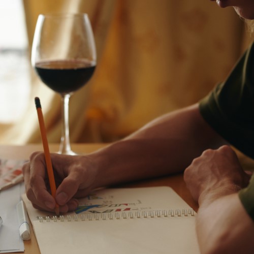 Pessoa bebendo vinho e colorindo.