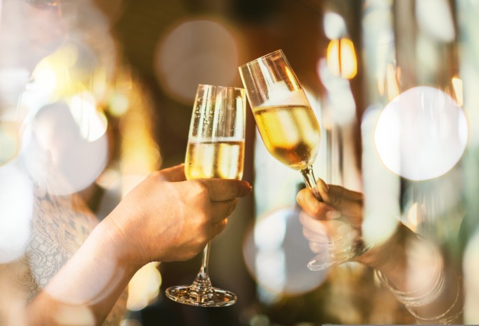 Duas pessoas brindando com taça de espumante.