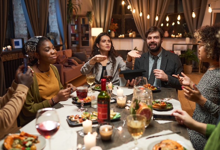 Pessoas conversando em um jantar com bebidas e comidas na mesa