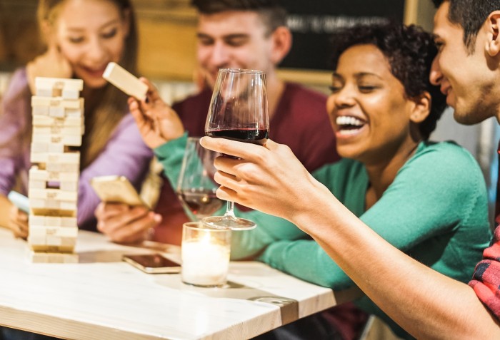 Quatro pessoas se divertindo brincando com uma torre de peças que está sobre uma mesa
