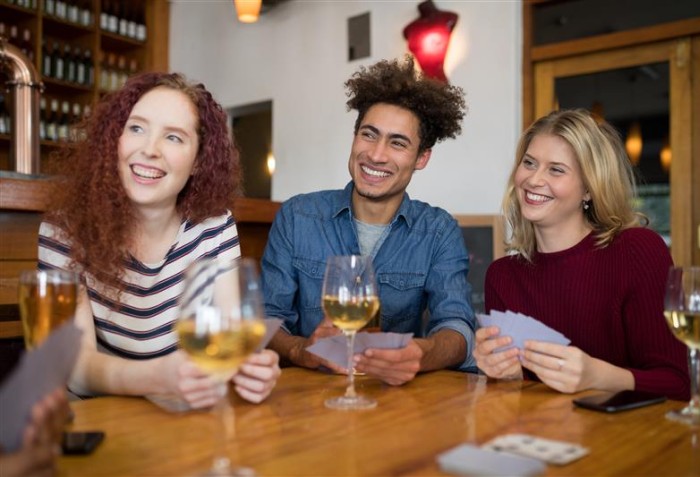 Três pessoas sorrindo com taças de bebidas na mesa