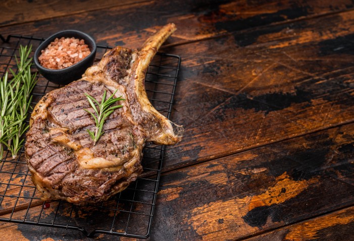Peça de carne com osso em cima de uma grelha