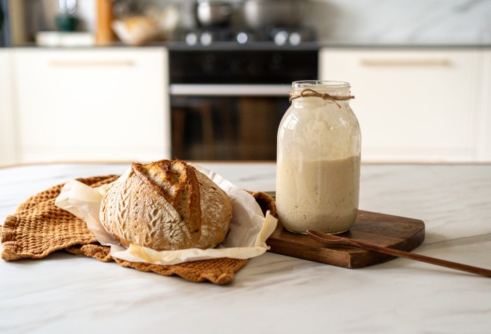 Um pão e um pote de vidro ao lado com trigo