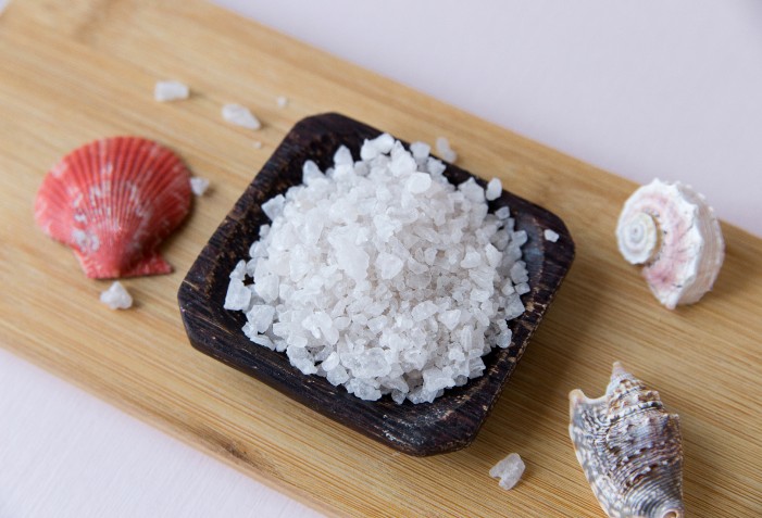 Sal marinho em um pote com elementos marinhos ao lado.