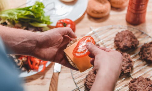 Mãos De Um Homem Montando Um Hamburguer.