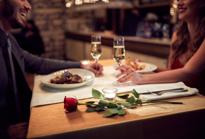 Um casal jantando e sorrindo um para o outro.