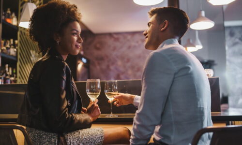 Um Casal Sentados Se Olhando E Segurando Taças De Vinho.