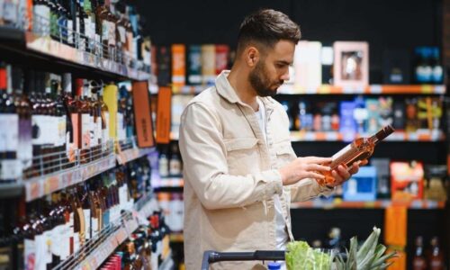 Homem Avaliando Rótulo De Uma Garrafa De Vinho No Mercado.