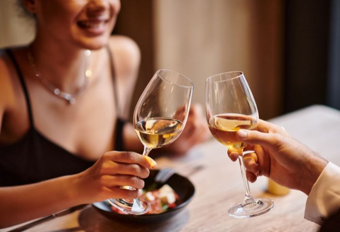 Casal em restaurante brindando com vinho.