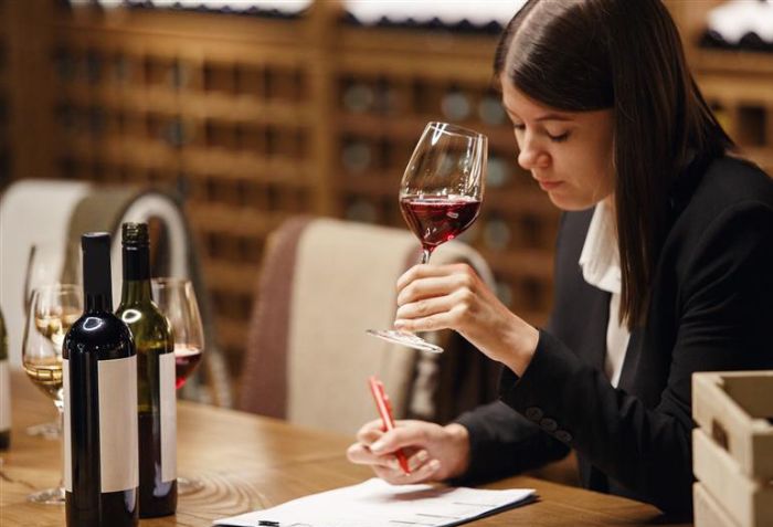 Mulher com taça de vinho na mão e escrevendo