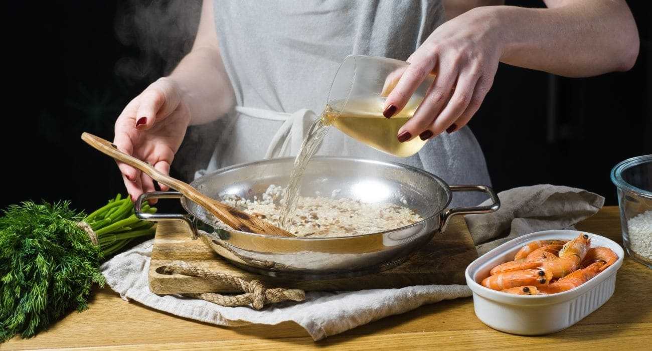 Mulher Preparando Risoto E Utilizando Vinho Branco Como Parte Da Receita.